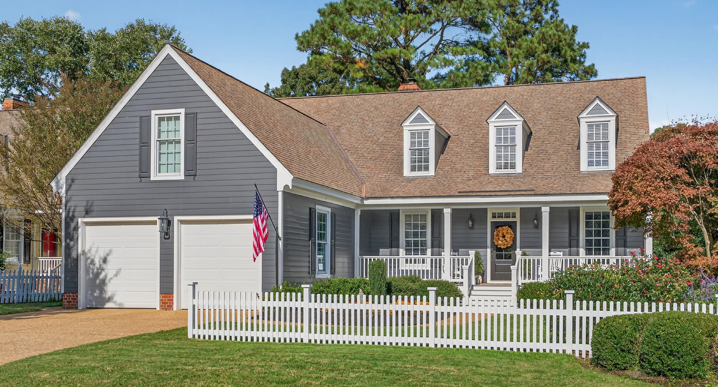 164 Highland — a gray Cape Cod home with a white picket fence and American flag, on the 18th fairway of Marsh Hawk at Ford's Colony