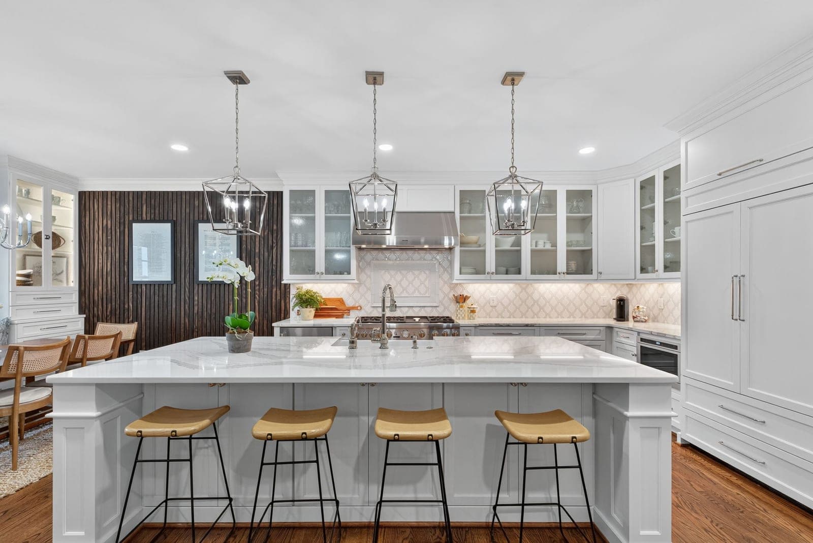 The renovated kitchen at 164 Highland: a marble waterfall island with lantern pendants and brass-accented stools