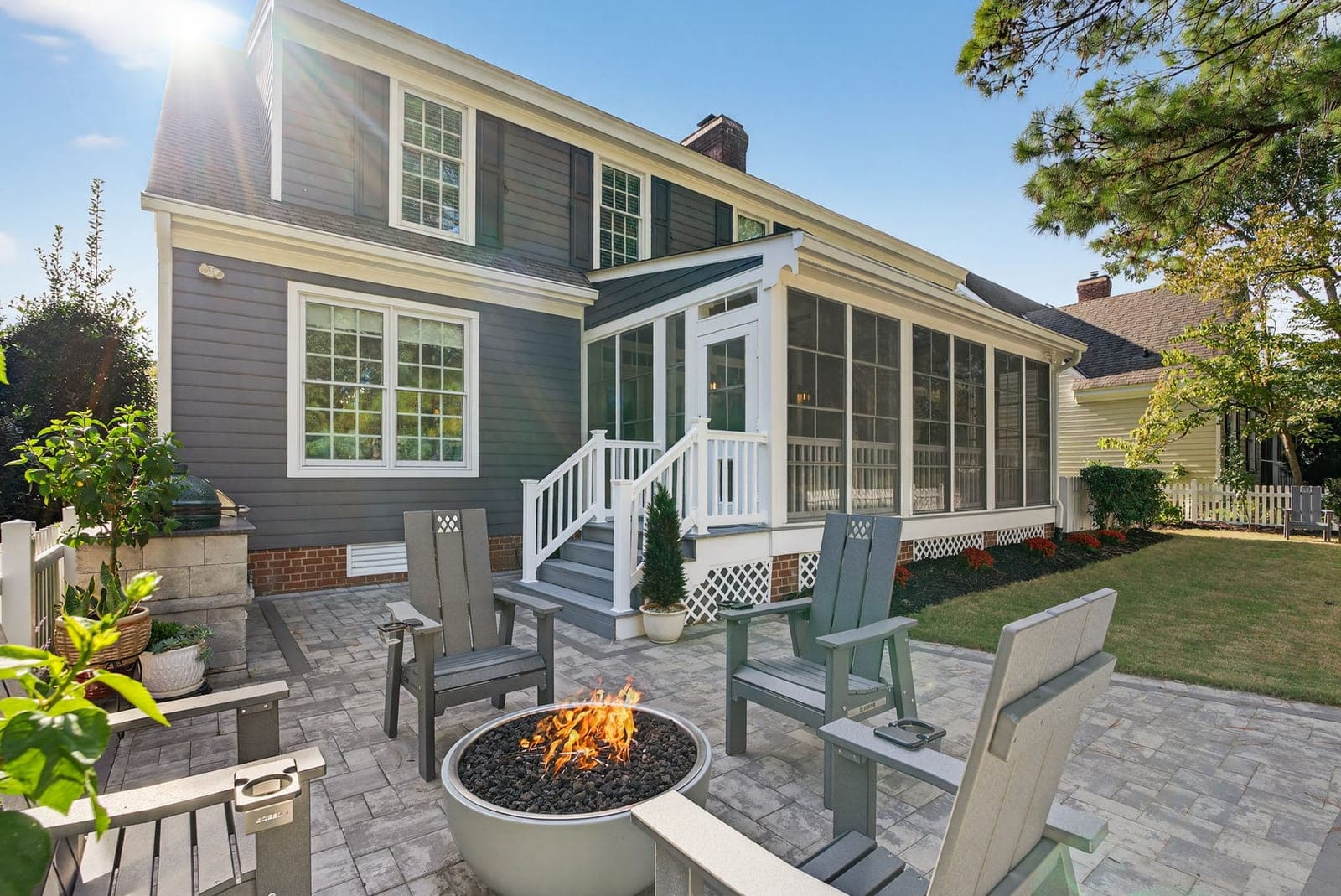 The rear paver patio at 164 Highland with a fire pit, Adirondack seating, and the screened porch beyond